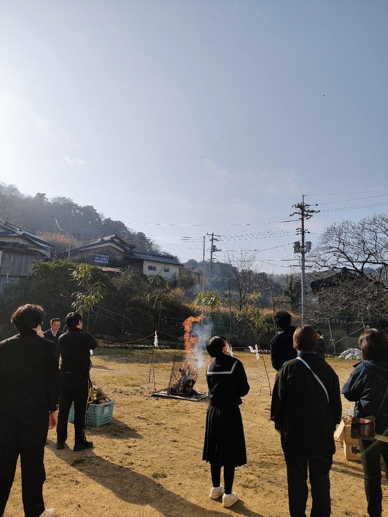 野島でのどんど焼き。炎に書初めを投じる子供たちと周囲で見守る島民。