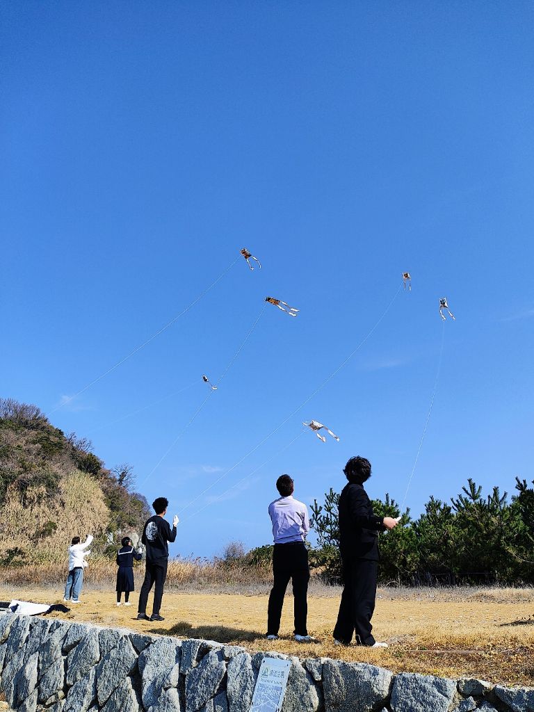 防府市野島の津久美浜で凧揚げを楽しむ子供たちと保護者。