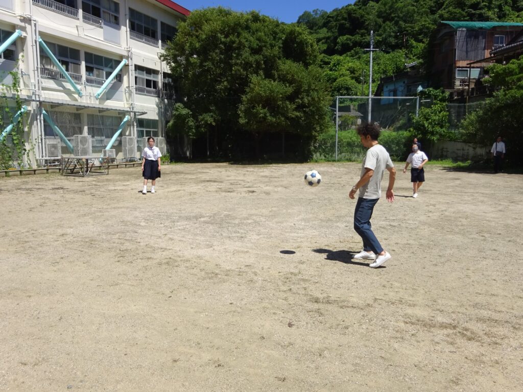 野島小中学校のグラウンドでレノファ山口FCの役員関係者やスタッフとサッカーを楽しむ児童たちの姿